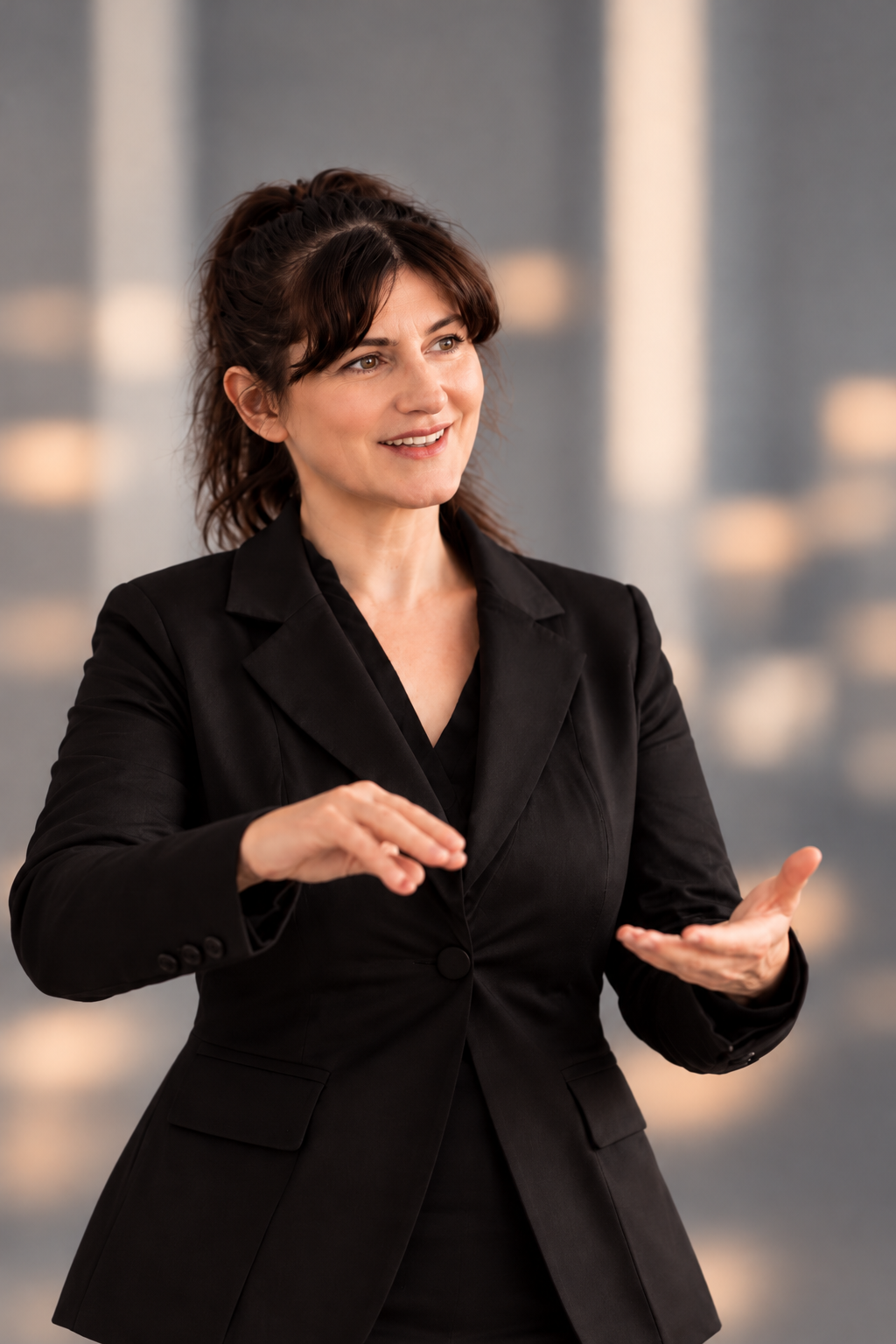 Dr. Arlena Jung von ChangeLab Organisationsberatung, lächelnd mit offener Handgestik und schwarzem Blazer